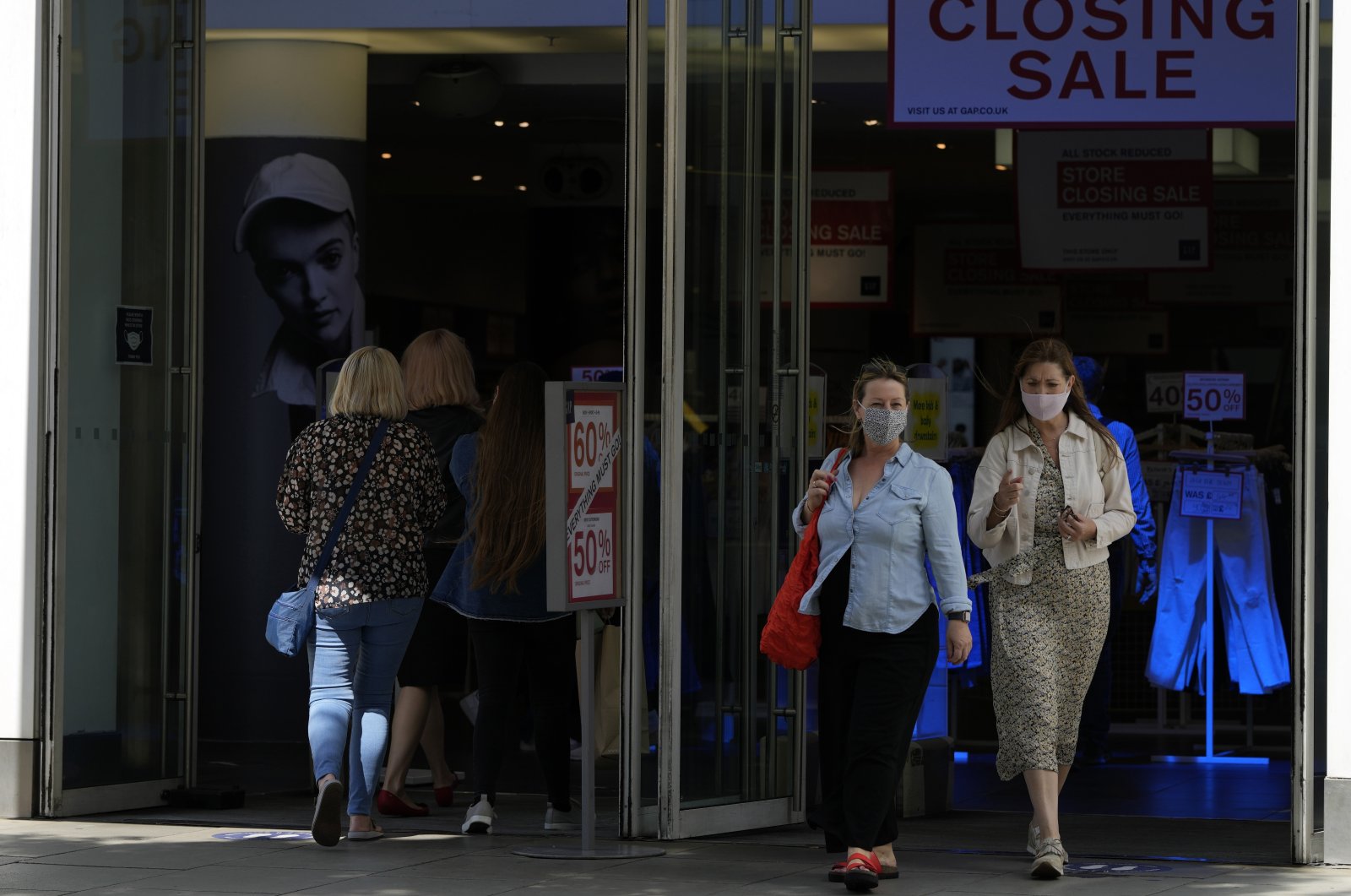 Two women walk from a shop while wearing face masks against the coronavirus in London, U.K., Friday, Aug. 6, 2021. (AP Photo)