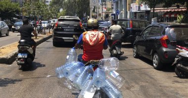 A man rides his scooter with empty water bottles, in Beirut, Lebanon, June 23, 2021. (AP Photo)
