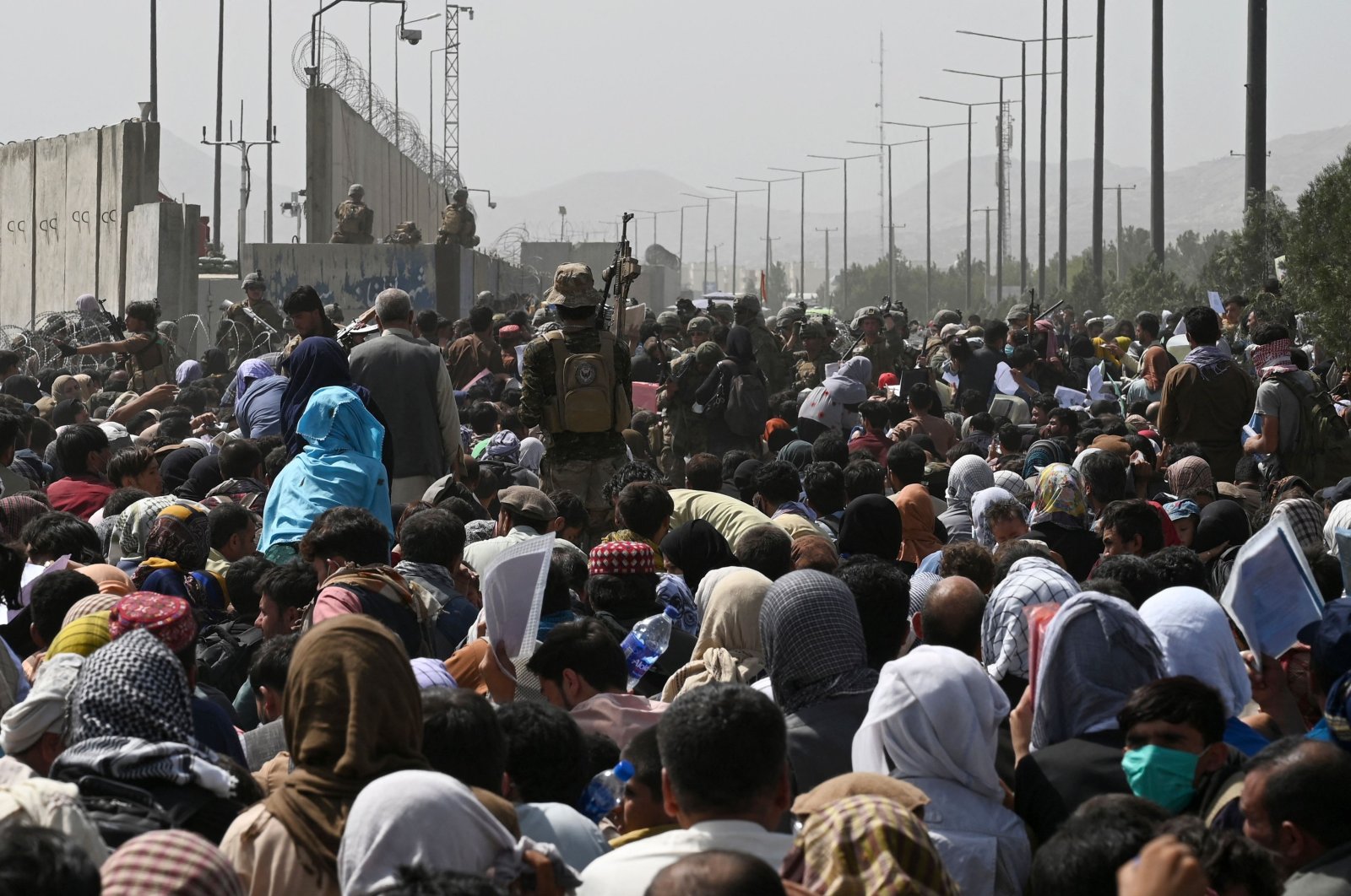 Afghans gather on a roadside near the military part of the airport in Kabul, Afghanistan, Aug. 20, 2021, hoping to flee from the country after the Taliban's military takeover. (AFP Photo)