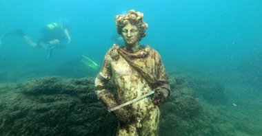A dive guide shows tourists a copy of the original statue preserved at the Museum of Baiae in the submerged ancient Roman city of Baiae, Pozzuoli near Naples, Italy, Aug. 18, 2021. (AFP Photo)