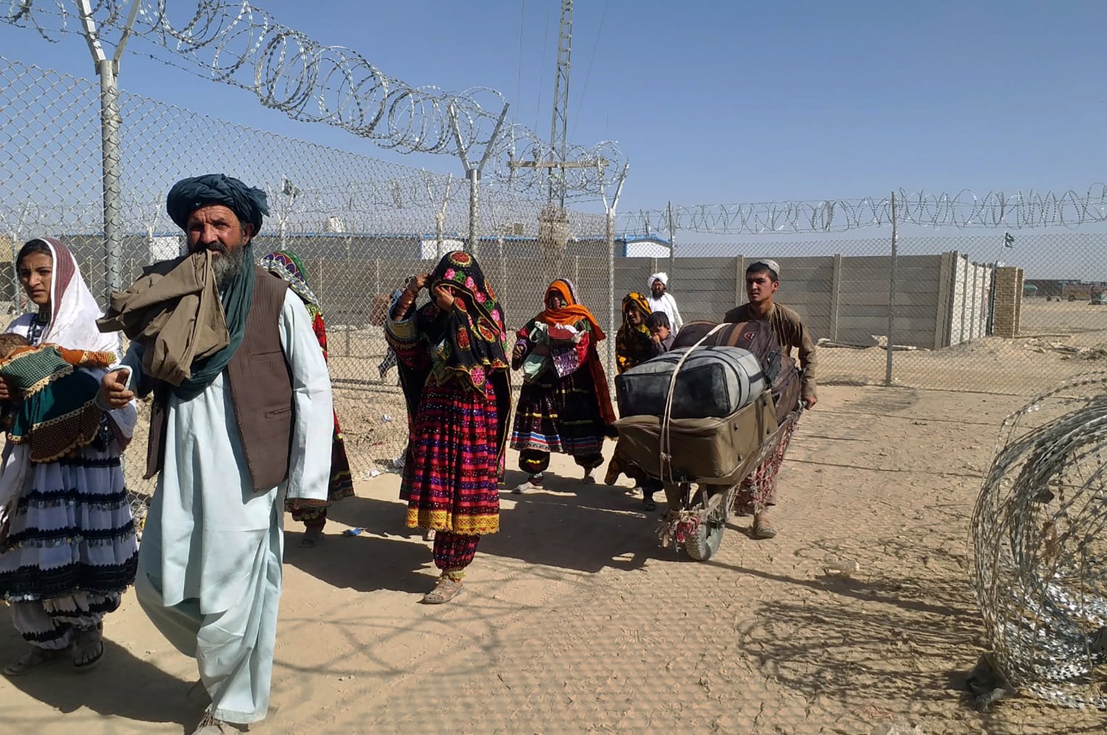 Afghan families enter Pakistan through a border crossing point in Chaman, Pakistan, Sunday, Aug. 22, 2021. (AP Photo)