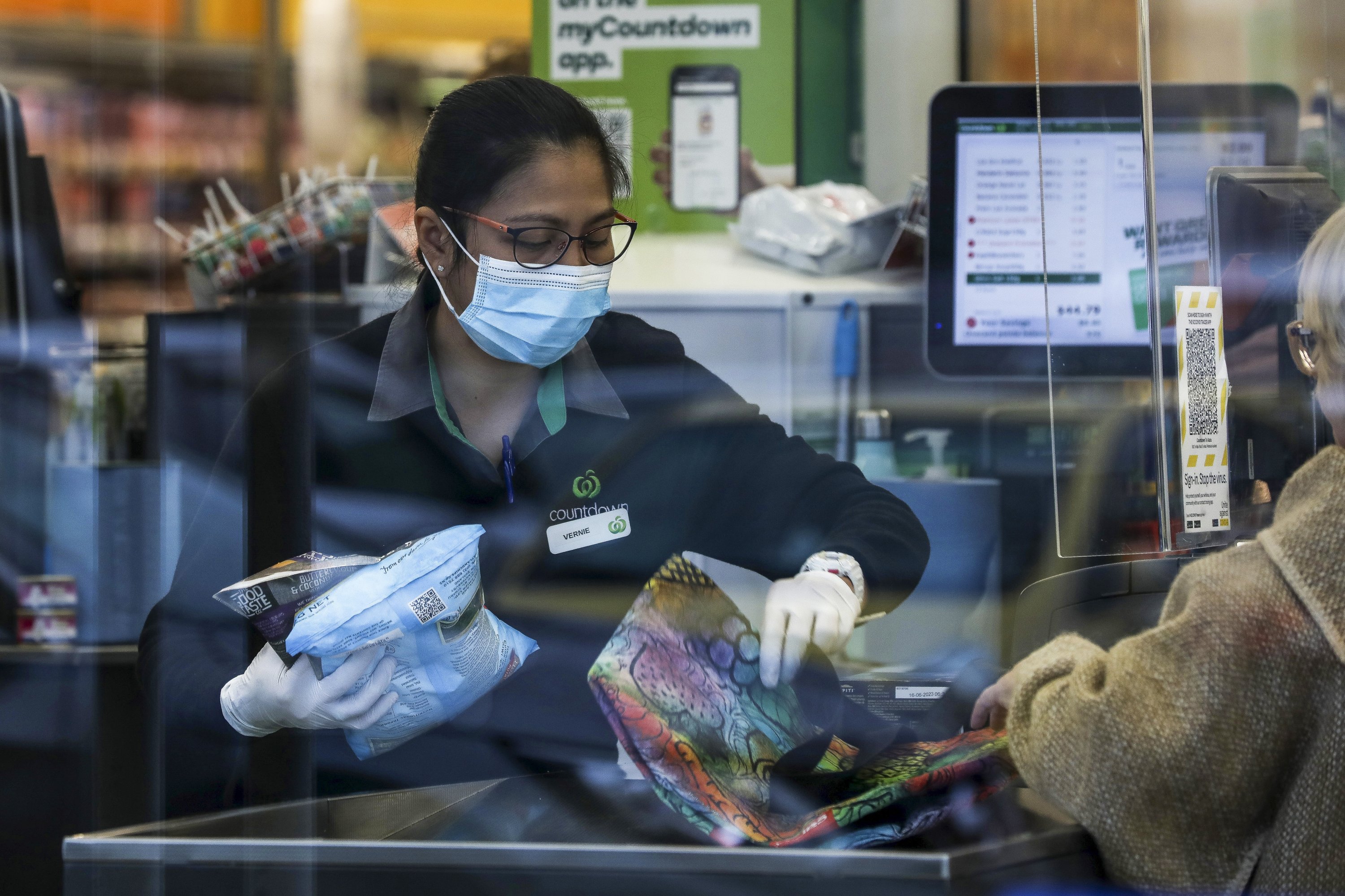 Supermarket staff help a customer with her shopping in Auckland, New Zealand, Aug. 17, 2021. (Hayden Woodward/New Zealand Herald via AP)
