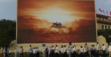 Attendees at a ceremony to mark the 100th anniversary of the founding of the ruling Chinese Communist Party pass by a screen depicting China's Mars spacecraft with its rover landing, in Beijing, China, July 1, 2021. (AP Photo)
