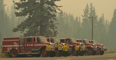 Cal Fire vehicles line up along Highway 50 in Strawberry, California, as smoke from the Caldor Fire burning on both sides of the route fills the air, Calif, U.S., Sunday, Aug. 22, 2021. (Sara Nevis / The Sacramento Bee via AP)