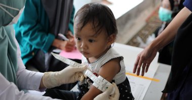 A nurse measures a child at The Children Community Health Care in Ulee Kareng, Banda Aceh, Indonesia, 24 August 2021. (EPA Photo) 