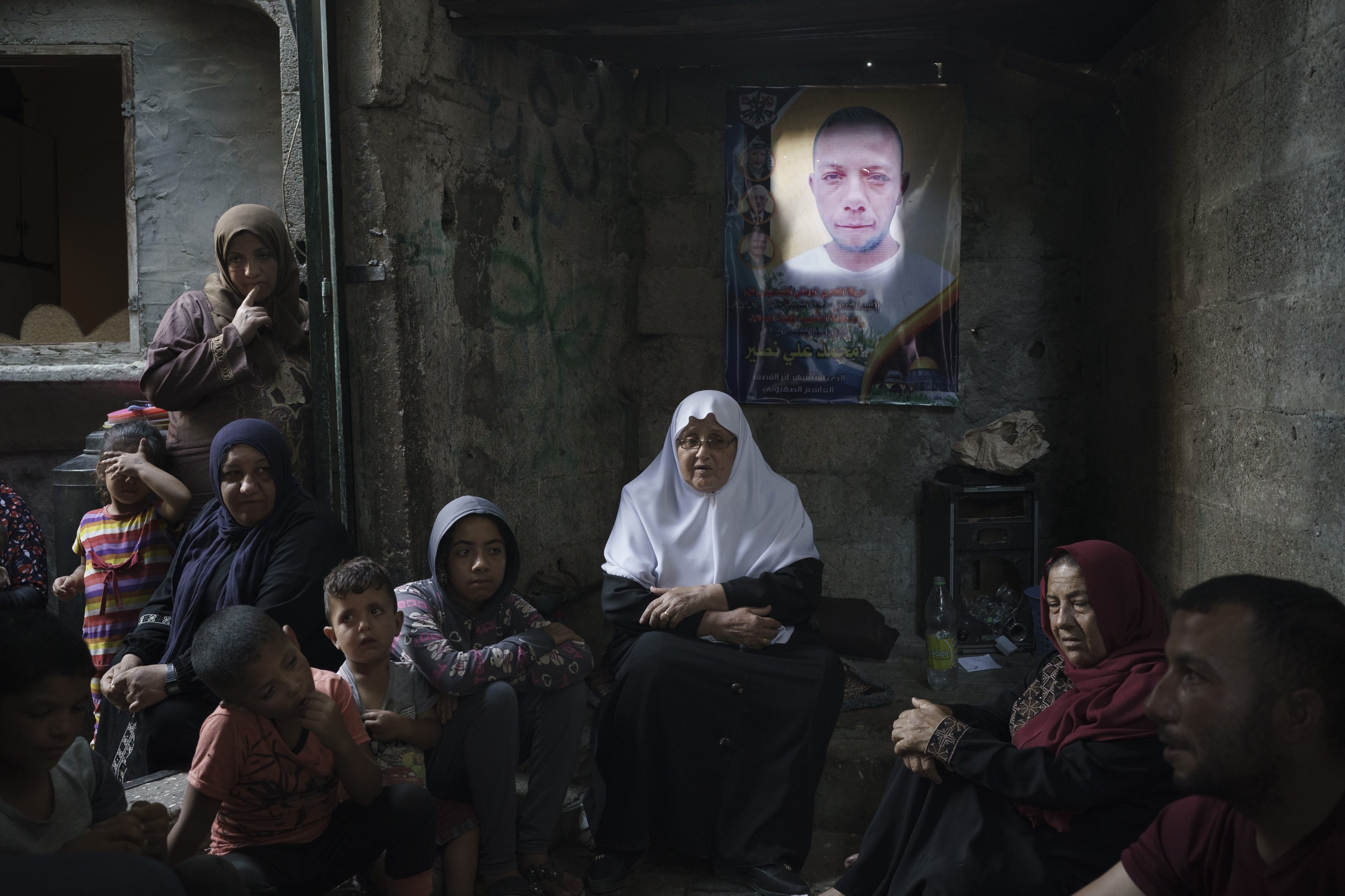 Members of the Nassir family sit under a poster of Mohamed Nassir, who died in the recent 11-day war between Israel and Hamas, June 12, 2021 in Beit Hanoun, northern Gaza, Palestine. (AP Photo)