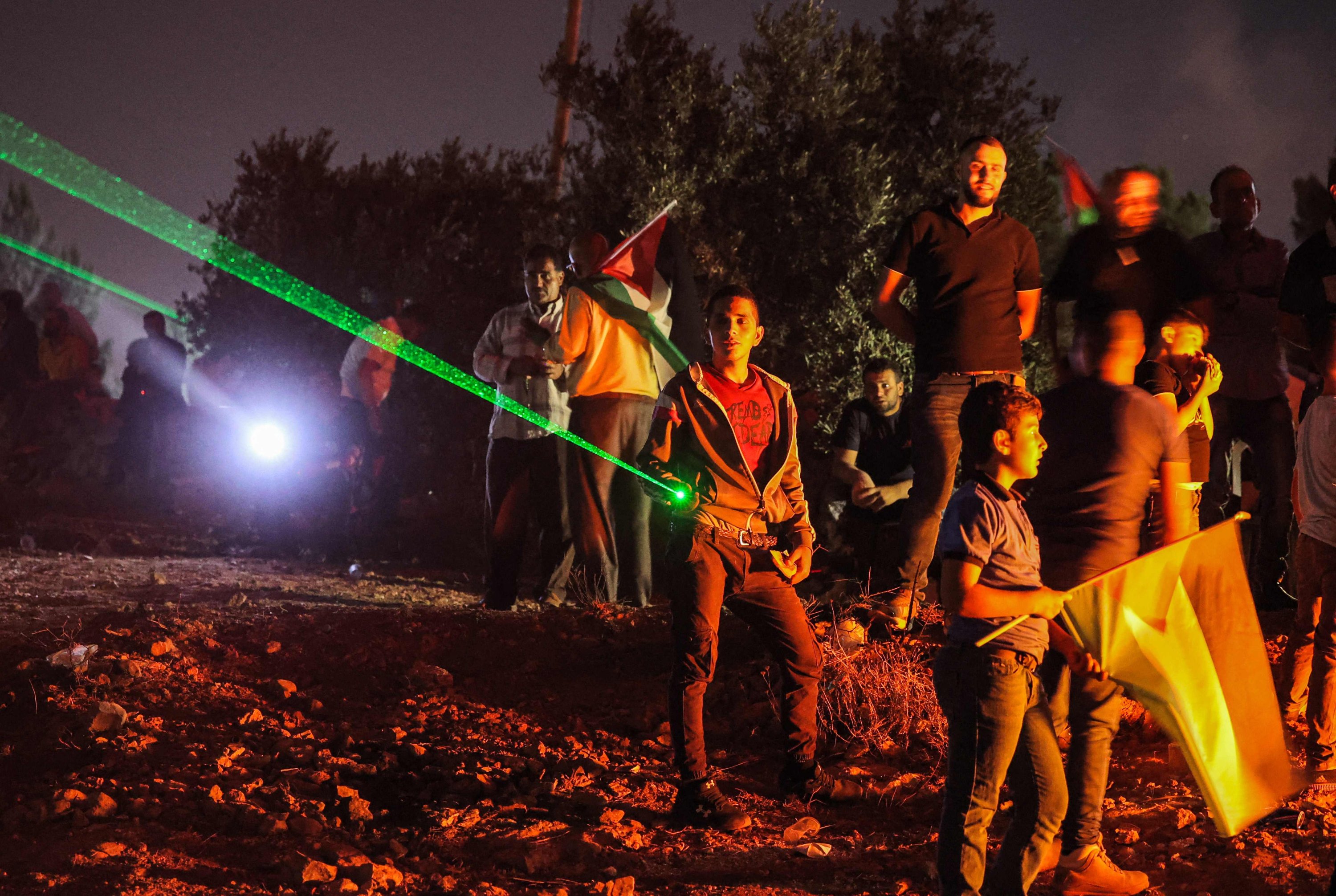 Palestinian protesters use laser torches during a demonstration against the Israeli settlers