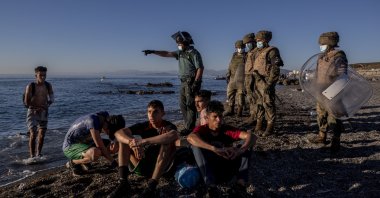 Migrants are surrounded by Spanish security forces on a beach after arriving at the Spanish enclave of Ceuta, near the border of Morocco and Spain, May 19, 2021. (AP Photo)