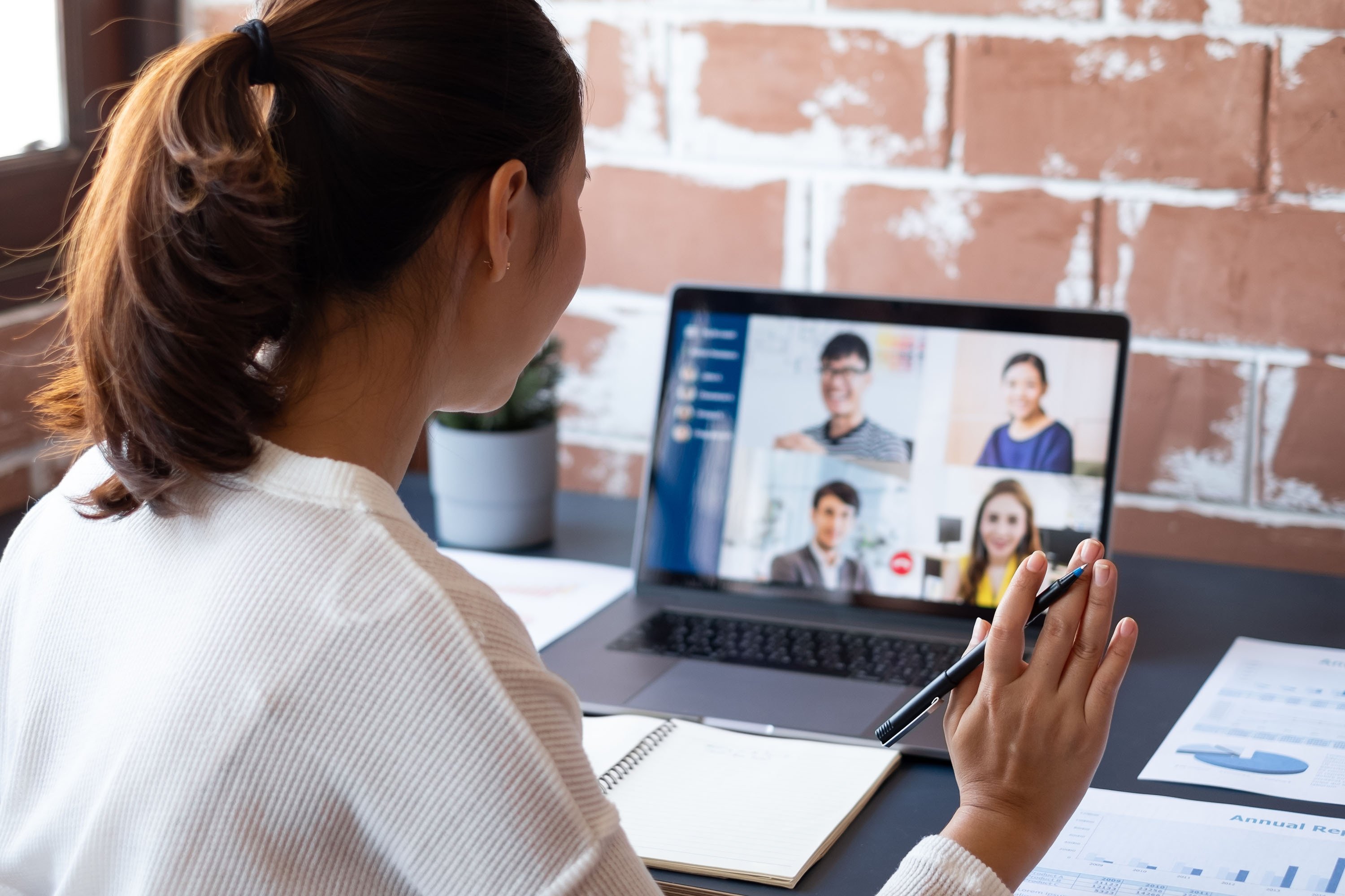 A young employee attends a virtual video conference meeting with colleagues. (Shutterstock Photo)