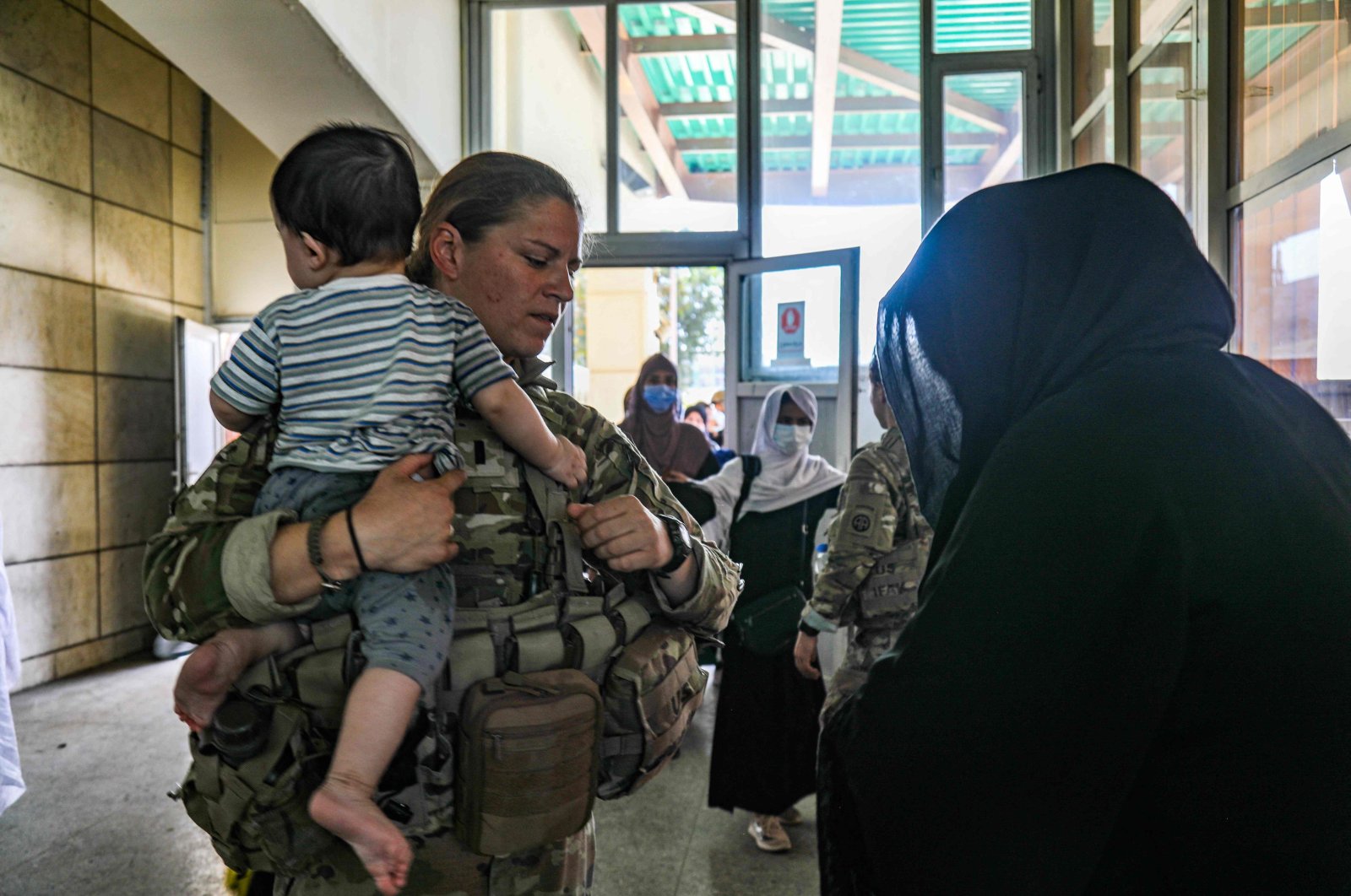 A medical officer assigned to the 82nd Airborne Division speaks with an Afghan woman and helps her with her child as part of the ongoing noncombatant evacuation of U.S. civilian personnel, Special Immigrant Visa applicants, and other at-risk individuals from Afghanistan from Hamid Karzai International Airport in Kabul, Afghanistan, Aug. 25, 2021. (AFP Photo)