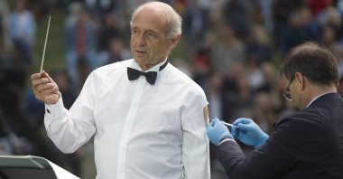 Ivan Fischer, the founder of the Budapest Festival Orchestra, receives his third dose of the COVID-19 vaccine as he conducts the orchestra, during their free concert in Budapest, Hungary, Aug. 25, 2021. (AP Photo)