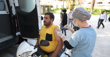 A man sits on his motorcycle while a nurse vaccinates him, in Şanlıurfa, southeastern Turkey, Aug. 27, 2021. (AA PHOTO) 