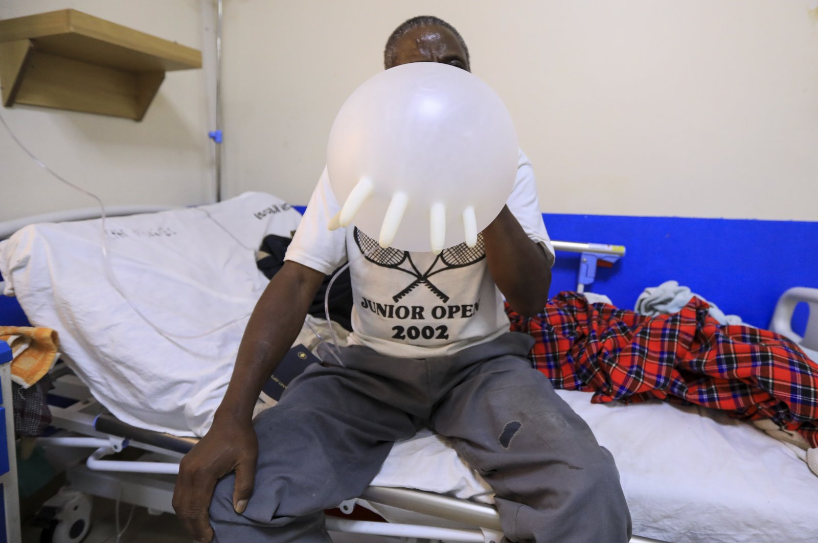 A COVID-19 patient inflates a balloon to exercise his lungs while inside an Intensive Care Unit (ICU) at the Machakos Level 5 hospital in Machakos, Kenya, Aug. 26, 2021. (EPA Photo)