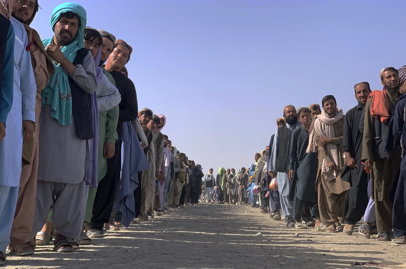 Afghan nationals line up and wait for security checks in Pakistan before entering Afghanistan through a common border crossing point in Chaman, Pakistan, Aug. 26, 2021. (AP Photo)