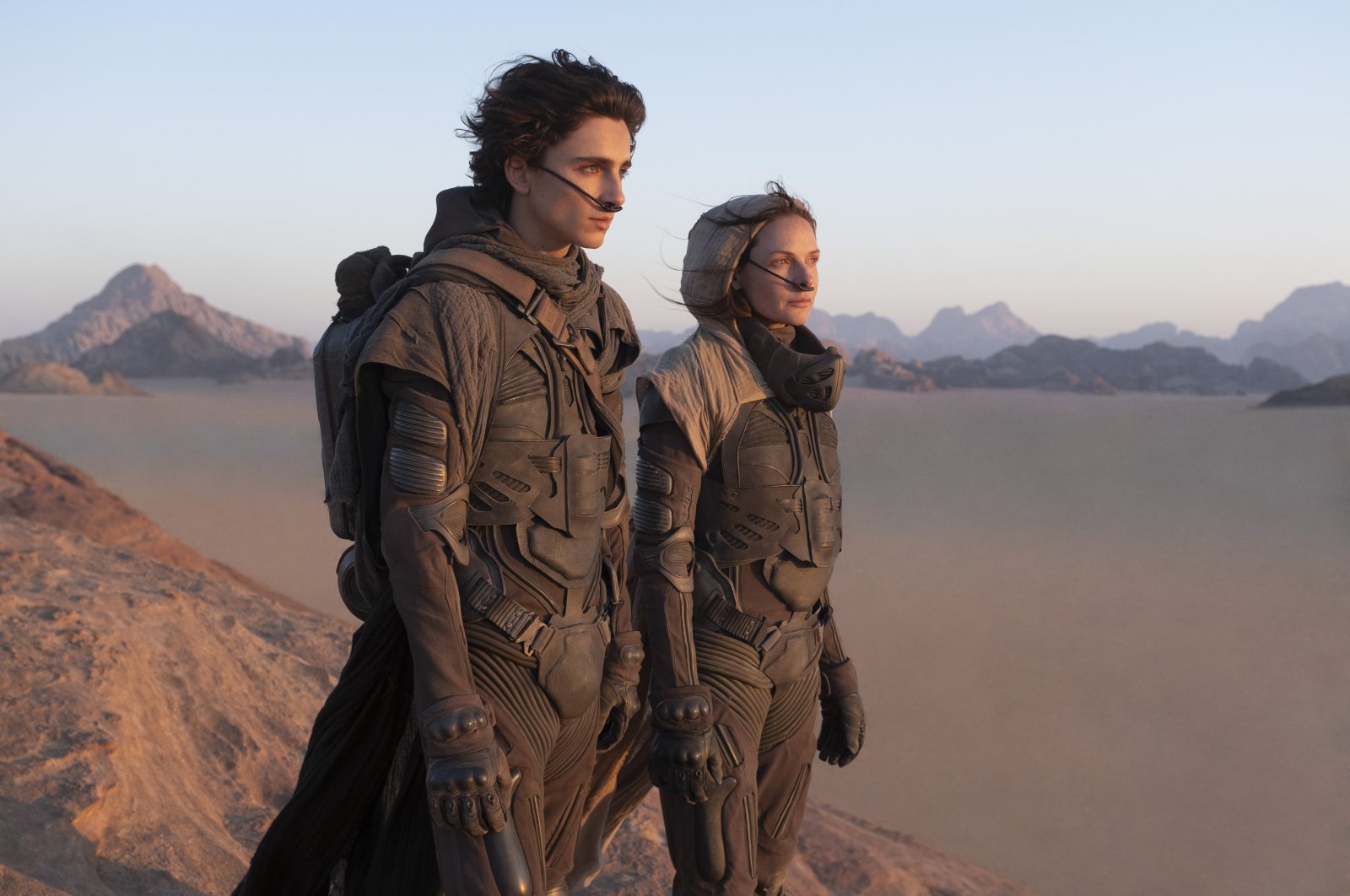 Timothee Chalamet (L), and Rebecca Ferguson look off into the distance, in a scene from the film "Dune." (Warner Bros. via AP)