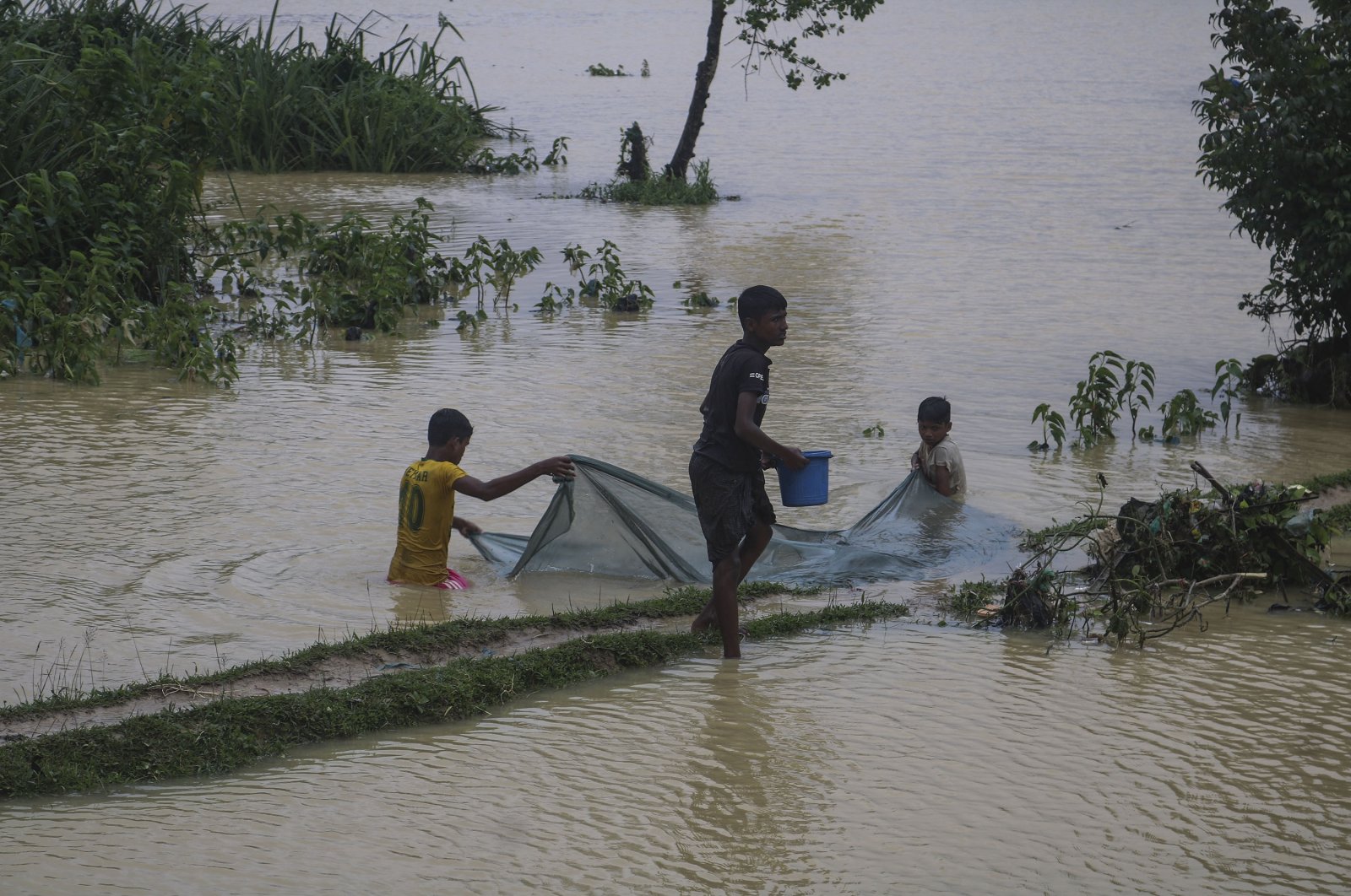 Rohingya refugees fish in flood waters following heavy rains at the Rohingya refugee camp in Kutupalong, Bangladesh, July 28, 2021. (AP Photo)