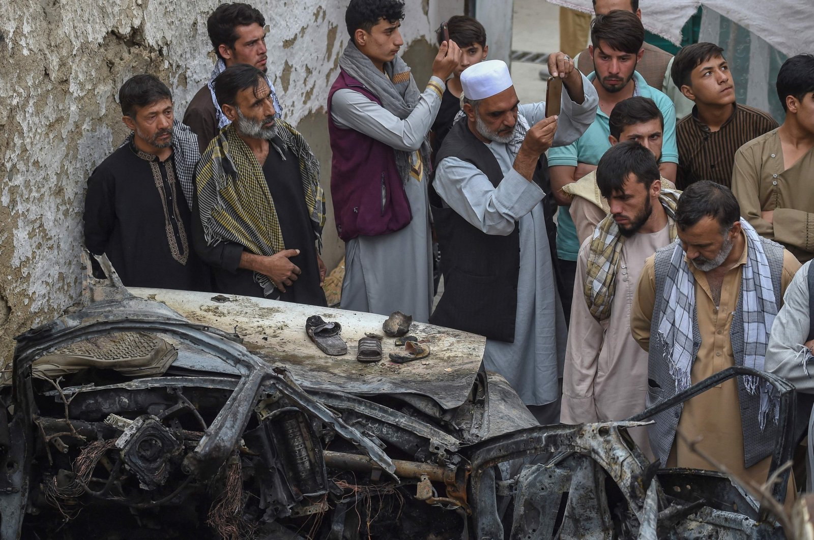 Afghan residents and family members of victims gather next to a damaged vehicle inside a house, the day after a U.S. drone airstrike in Kabul, Afghanistan, Aug. 30, 2021. (AFP Photo)