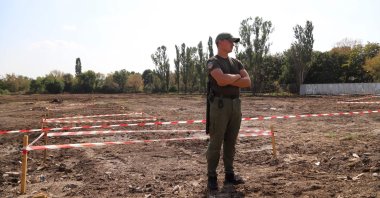 A security person stands guard at the mass graves site discovered on an abandoned area near the city airport where until recently was a dump in Odessa, Ukraine, Aug. 30, 2021. (AFP Photo)