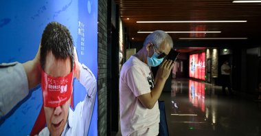 Visually impaired massage therapist Zhang Xinsheng uses his phone in front of a billboard supporting visually impaired people, at a cinema in Beijing, China, Aug. 7, 2021. (AFP Photo)