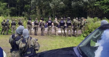 Migrants are seated, after crossing the border from Belarus into Poland in the village of Usnarz Gorny, Poland,  Aug. 19, 2021. (AP Photo)