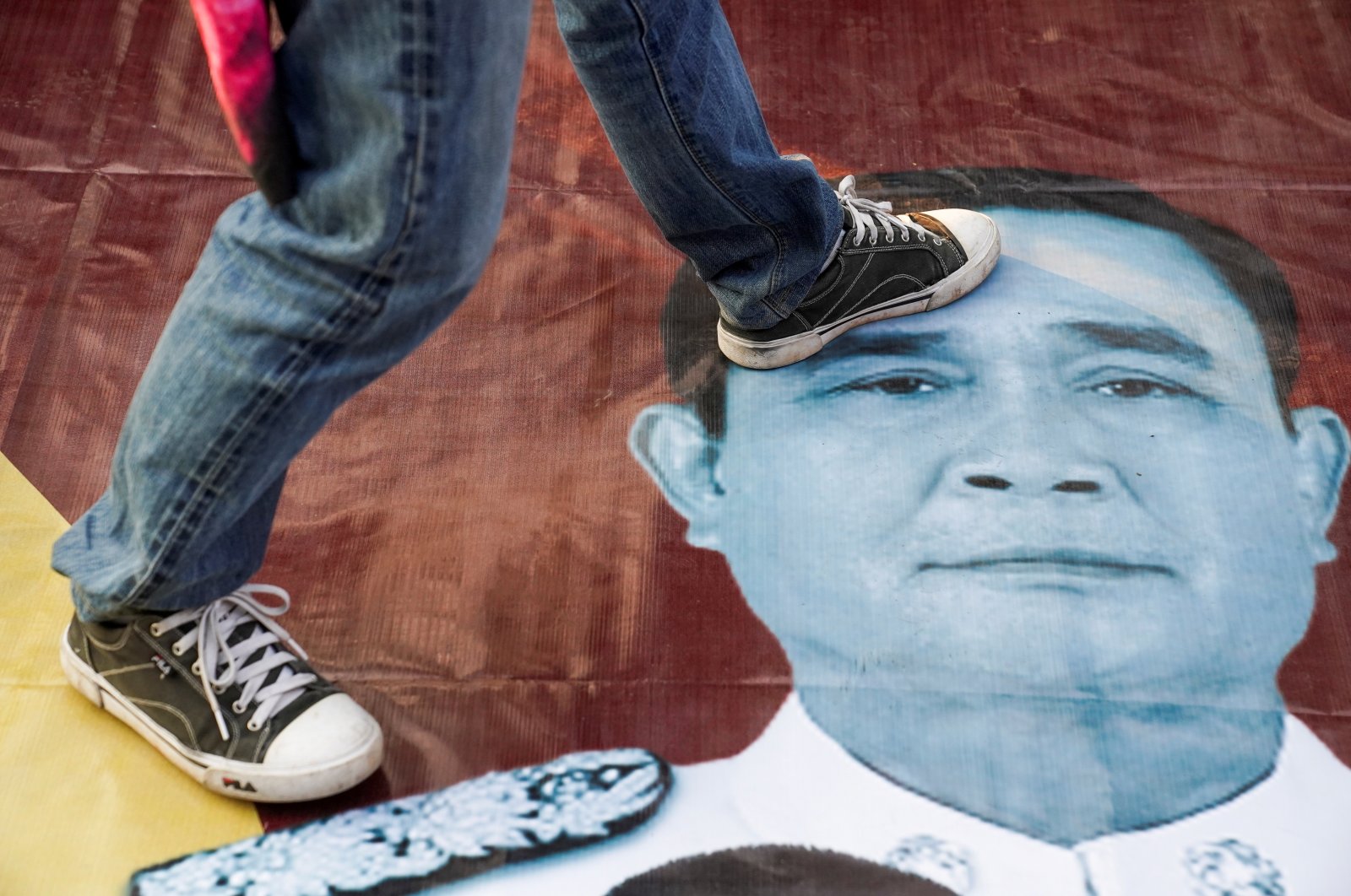 A protester steps on an image of Thailand's Prime Minister Prayuth Chan-ocha during a rally after he and nine ministers survived no-confidence debates, outside parliament in Bangkok, Thailand, Feb. 20, 2021. (Reuters File Photo)