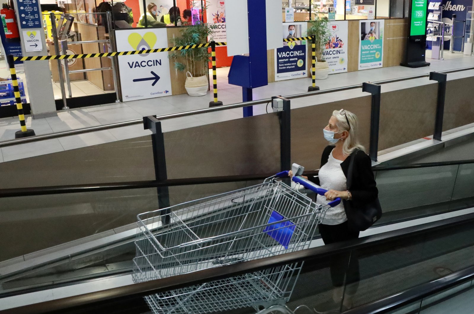 A woman pushes a shopping trolley past a sign for a COVID-19 vaccination center installed inside a supermarket in Brussels, Belgium, Aug. 30, 2021. (Reuters Photo)