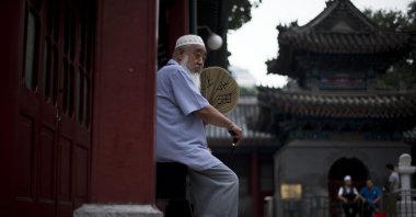 A Chinese Muslim man fans himself as he waits for the time to break his fast during the Muslim holy month of Ramadan at the Niujie mosque, the oldest and largest mosque in Beijing, China, July 2, 2014. (AP Photo)