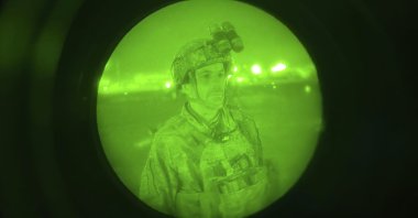 In this image made through a night vision scope and provided by the U.S. Army, Maj. Gen. Chris Donahue, commander of the U.S. Army 82nd Airborne Division, XVIII Airborne Corps, prepares to board a C-17 cargo plane at Kabul Hamid Karzai International Airport, Afghanistan, Aug. 30, 2021, as the final American service member to depart Afghanistan. (Master Sgt. Alexander Burnett/U.S. Army via AP)