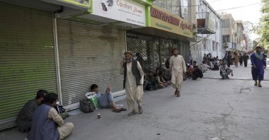 Afghans line a mostly shuttered market for hours to try to withdraw money from a nearby bank, in Kabul, Afghanistan,  Aug. 15, 2021. (AP Photo)