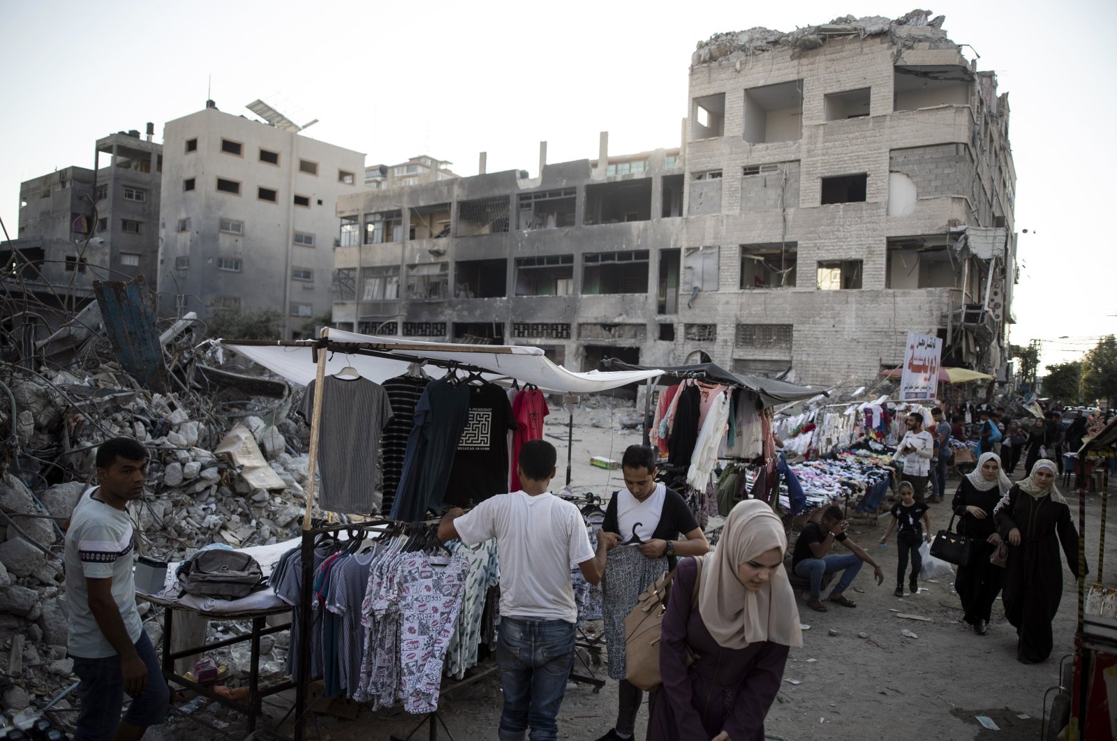 Palestinian street vendors display clothes for sale next to the rubble of destroyed buildings that were hit by Israeli airstrikes in Gaza City, Palestine, July 18, 2021. (AP Photo)