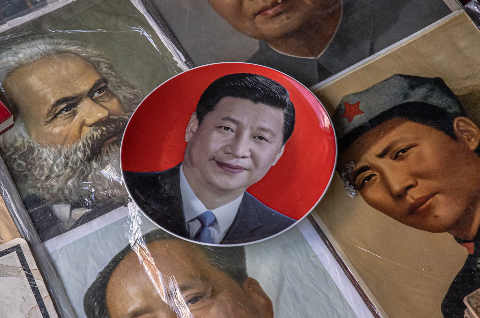 A plate with a picture of Chinese President Xi Jinping lays next to pictures of former leader Mao Zedong and German philosopher and revolutionary socialist Karl Marx, at the Panjiayuan antique market in Beijing, China, Aug. 26, 2021. (EPA Photo)