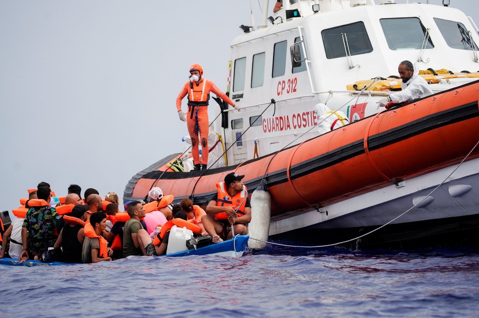 Members of Italy's Guardia Costiera prepare to bring on board migrants off a wooden boat near the Italian island of Lampedusa, in the Mediterranean Sea, Sept. 1, 2021. (Reuters Photo)