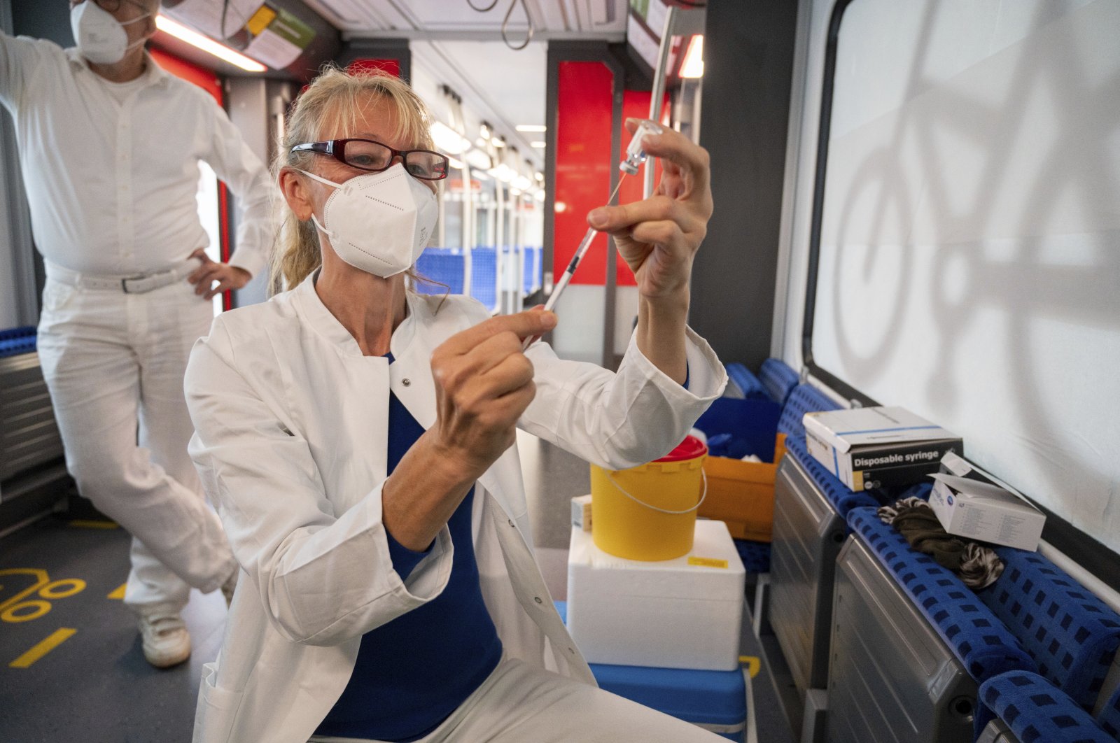 Yvonne Willmann, a railway employee, draws up a syringe with the Johnson & Johnson vaccine in a special train of the public transport organization S-Bahn, in which vaccinations against COVID-19 are offered, Berlin, Germany, Aug. 30, 2021. (AP Photo)