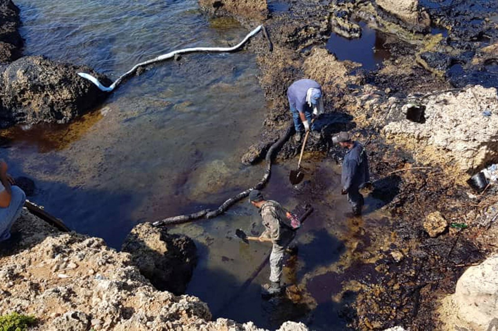 A handout picture released by the official Syrian Arab News Agency (SANA) shows people cleaning Syria's Mediterranean coast following an oil leak from the Baniyas power plant, Aug. 31, 2021. (AFP Photo)