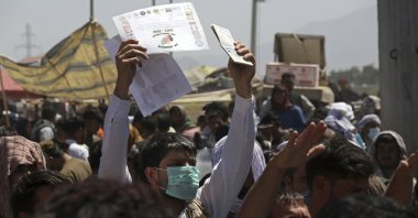 Hundreds of people gather, some holding documents, near an evacuation control checkpoint on the perimeter of the Hamid Karzai International Airport, in Kabul, Afghanistan, Aug. 26, 2021. (AP Photo)