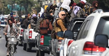 A man on his bicycle rides past a convoy of Taliban fighters patrolling along a street in Kabul, Afghanistan, Sept. 2, 2021. (AFP Photo)