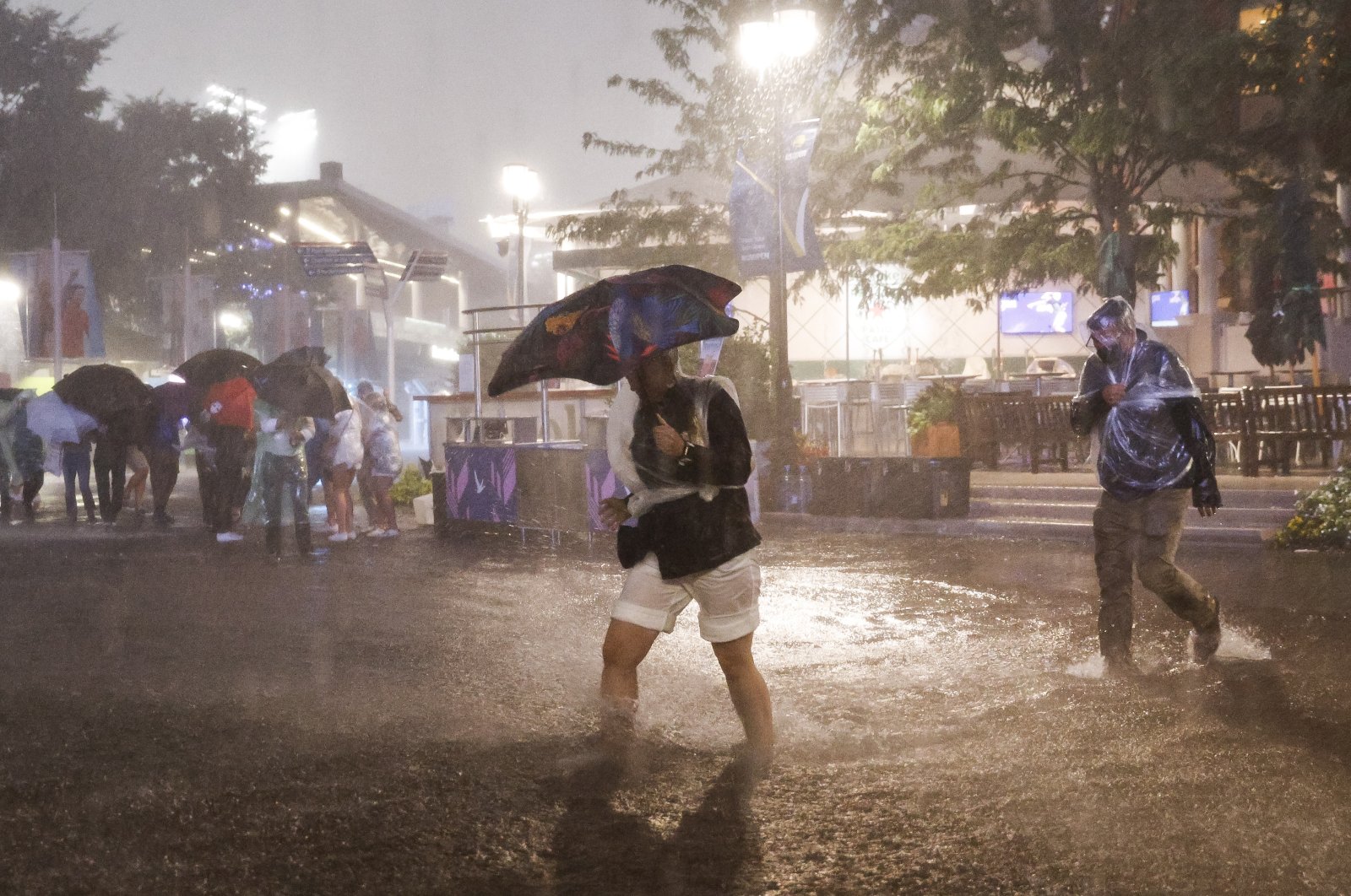 People navigate heavy rains and flooded walkways at the Billie Jean King National Tennis Center as the remnants of Hurricane Ida hit the area in Flushing Meadows, New York, U.S., Sept. 1, 2021.  (EPA Photo)