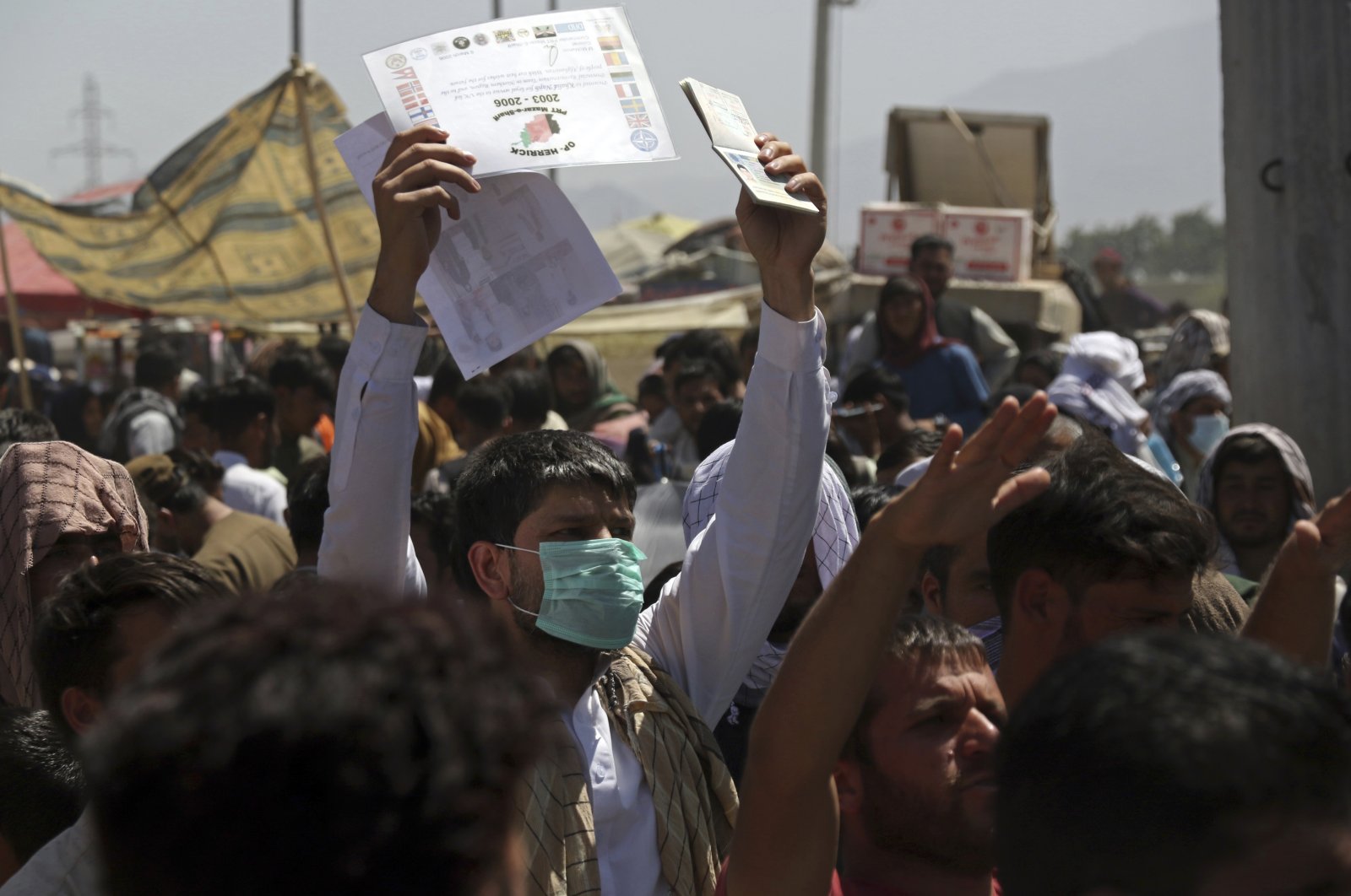 Hundreds of people gather, some holding documents, near an evacuation control checkpoint on the perimeter of the Hamid Karzai International Airport, in Kabul, Afghanistan, Aug. 26, 2021. (AP Photo)