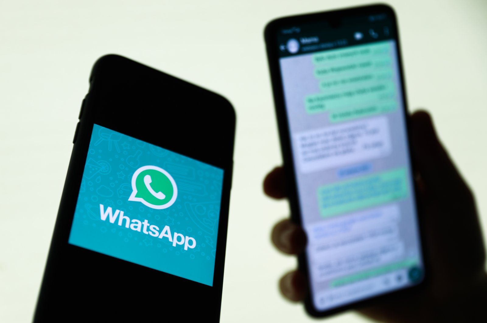 The WhatsApp logo is displayed on a phone screen and a conversation on WhatsApp is displayed on a phone screen in the background in this illustration photo taken in Krakow, Poland, Aug. 27, 2021. (Reuters File Photo)