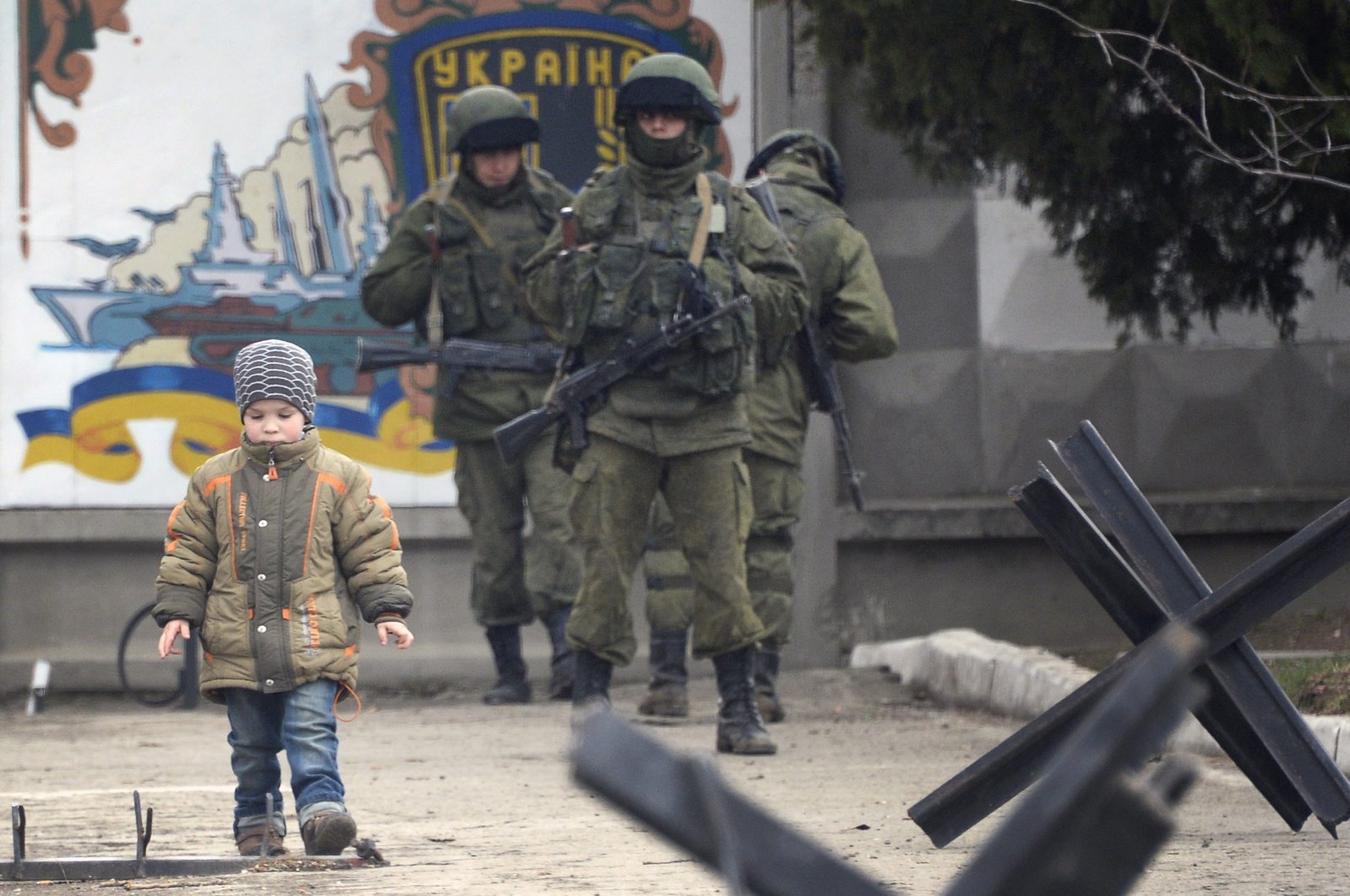 A boy passes in front of Russian forces blocking access to the base of the 36th detached brigade of the Ukrainian Navy's coastal guards, not far from the village of Perevalne, near Simferopol, Crimea, Ukraine, on March 5, 2014. (AFP Photo)