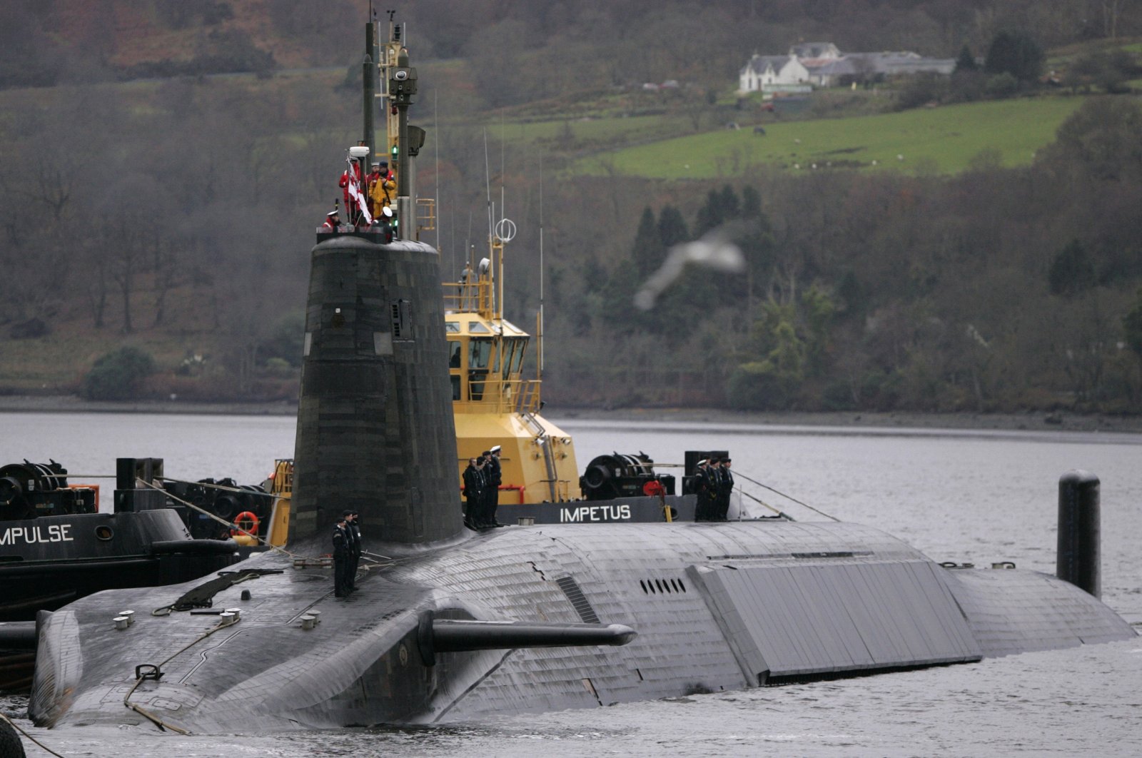 A crew from HMS Vengeance, a British Royal Navy Vanguard class Trident Ballistic Missile Submarine, stand on their vessel as they return along the Clyde river to the Faslane naval base near Glasgow, Scotland, Dec. 4, 2006. (Reuters Photo)