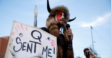 Jacob Chansley, holding a sign referencing QAnon, speaks as supporters of U.S. President Donald Trump gather to protest about the early results of the 2020 presidential election, in front of the Maricopa County Tabulation and Election Center, in Phoenix, Arizona, U.S., November 5, 2020. (REUTERS File Photo)