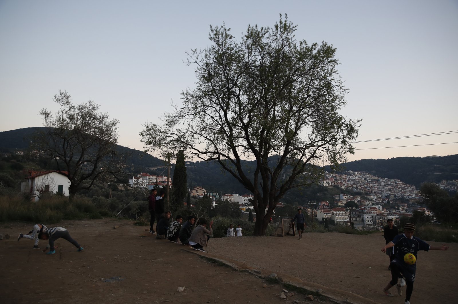 Migrants play football outside the perimeter of the overcrowded refugee camp at the port of Vathy on the eastern Aegean island of Samos, Greece, Feb. 23, 2021. (AP Photo)