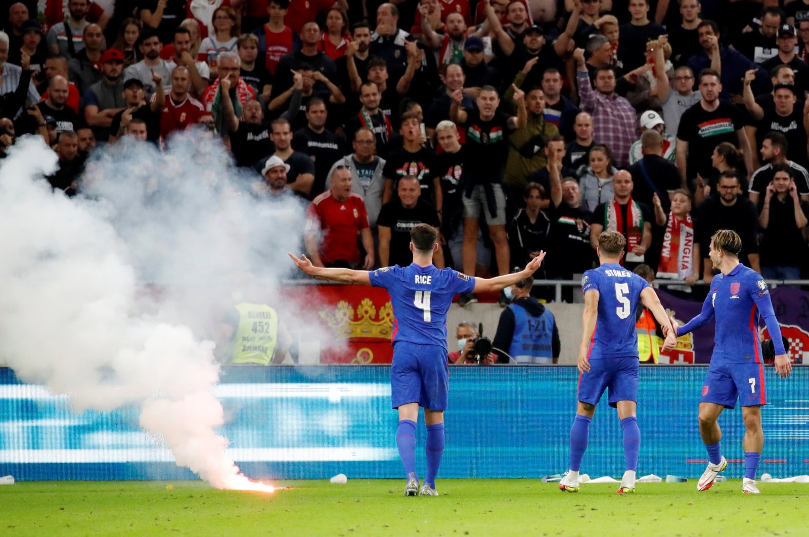 England's Declan Rice (L), John Stones (C) and Jack Grealish react after a flare is thrown onto the pitch by Hungary fans during a World Cup 2022 qualifiers at the Puskas Arena, Budapest, Hungary, Sept. 2, 2021.
