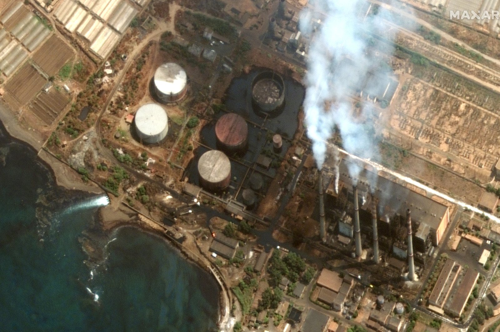 A handout satellite image made available by Maxar Technologies shows oil pooling around a set of oil storage tanks at the Baniyas power plant and spilling into the Mediterranean, in Baniyas, Syria, Aug. 28, 2021. (Photo by Maxar Technologies via EPA)