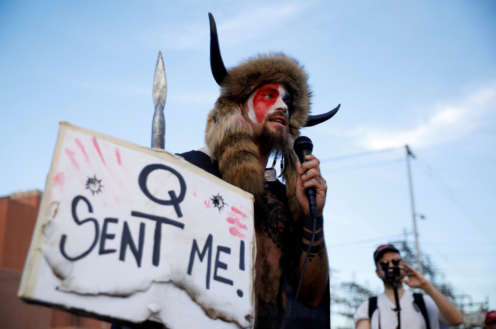 Jacob Chansley, holding a sign referencing QAnon, speaks as supporters of U.S. President Donald Trump gather to protest about the early results of the 2020 presidential election, in front of the Maricopa County Tabulation and Election Center, in Phoenix, Arizona, U.S., November 5, 2020. (REUTERS File Photo)
