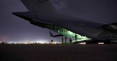 An Air Force aircrew, assigned to the 816th Expeditionary Airlift Squadron, prepares to receive soldiers, assigned to the 82nd Airborne Division, to board a U.S. Air Force C-17 Globemaster III aircraft in support of the final noncombatant evacuation operation missions at Kabul Hamid Karzai International Airport in Kabul, Afghanistan, Aug. 30, 2021. (Senior Airman Taylor Crul/U.S. Air Force via AP)