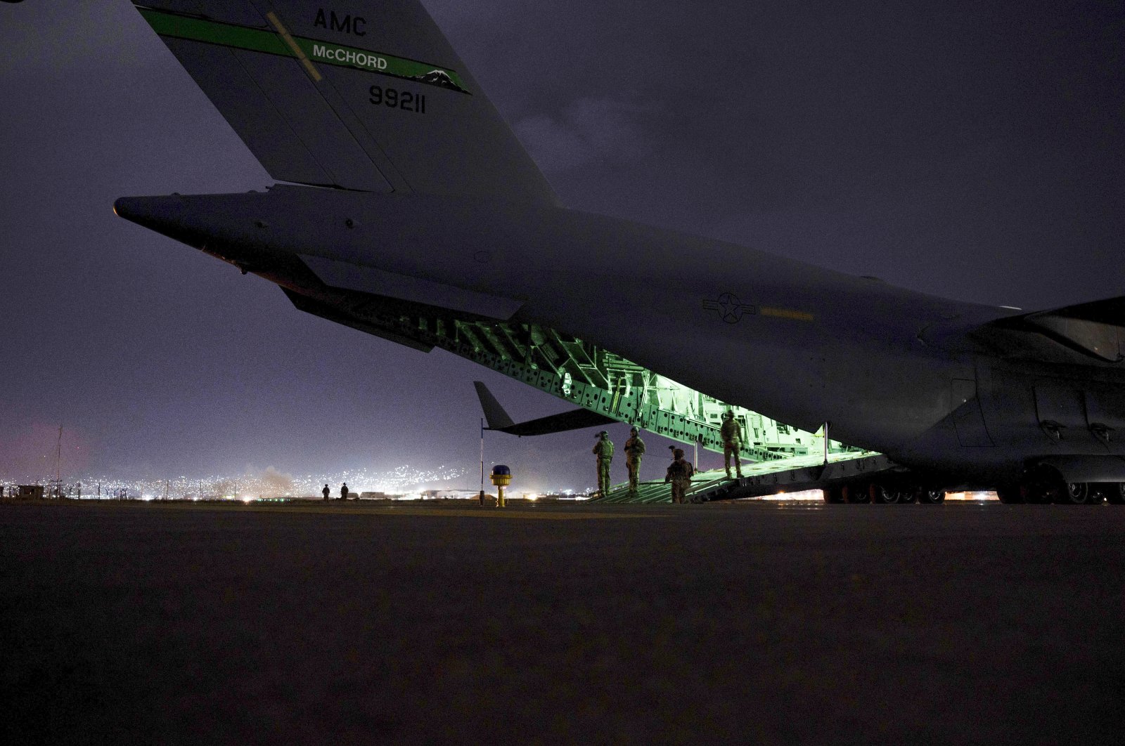 An Air Force aircrew, assigned to the 816th Expeditionary Airlift Squadron, prepares to receive soldiers, assigned to the 82nd Airborne Division, to board a U.S. Air Force C-17 Globemaster III aircraft in support of the final noncombatant evacuation operation missions at Kabul Hamid Karzai International Airport in Kabul, Afghanistan, Aug. 30, 2021. (Senior Airman Taylor Crul/U.S. Air Force via AP)