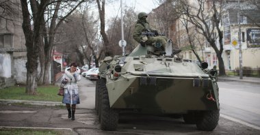 A woman walks past a Russian military personnel carrier outside a Ukrainian military base on March 18, 2014 in Simferopol, Ukraine. (Getty Images)