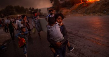 A boy carries a child in his arms as migrants flee the Moria camp after a fire broke out, on the island of Lesbos, Sept. 9, 2020. (AFP Photo)